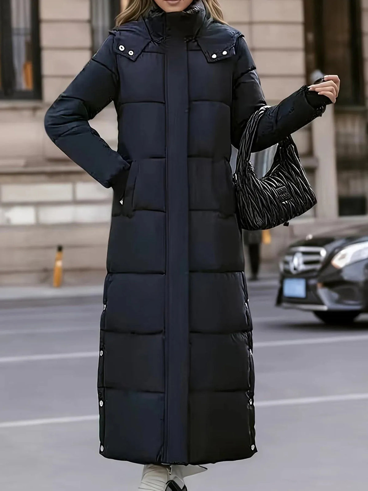 Thickened black trench coat above the knee with a slim fit and pockets, paired with a stylish black handbag.